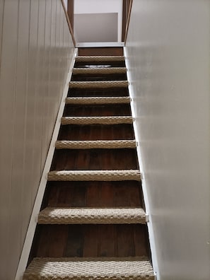 A wooden staircase with a white railing and a plain wall on one side. - Charming, peaceful vacation rental with a spa, near the beaches (Ver)