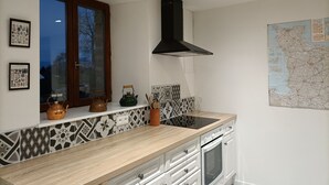 A kitchen with a wooden countertop, a black range hood, a window with a view, and a map on the wall. - Charming, peaceful vacation rental with a spa, near the beaches (Ver)