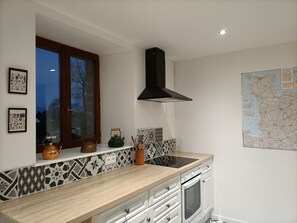 A kitchen with a wooden countertop, a black range hood, a window with a view, and a map on the wall. - Charming, peaceful vacation rental with a spa, near the beaches (Ver)