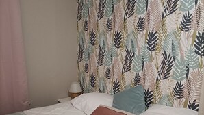 A bed with a patterned headboard, a bedside table with a lamp, and a pink curtain. - Charming, peaceful vacation rental with a spa, near the beaches (Ver)