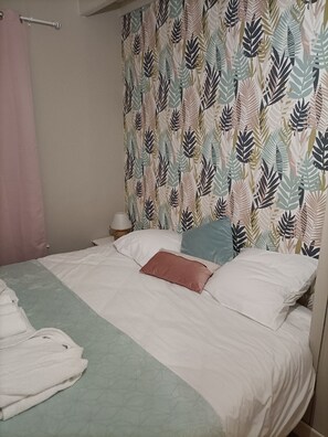 A bed with a patterned headboard, a bedside table with a lamp, and a pink curtain. - Charming, peaceful vacation rental with a spa, near the beaches (Ver)
