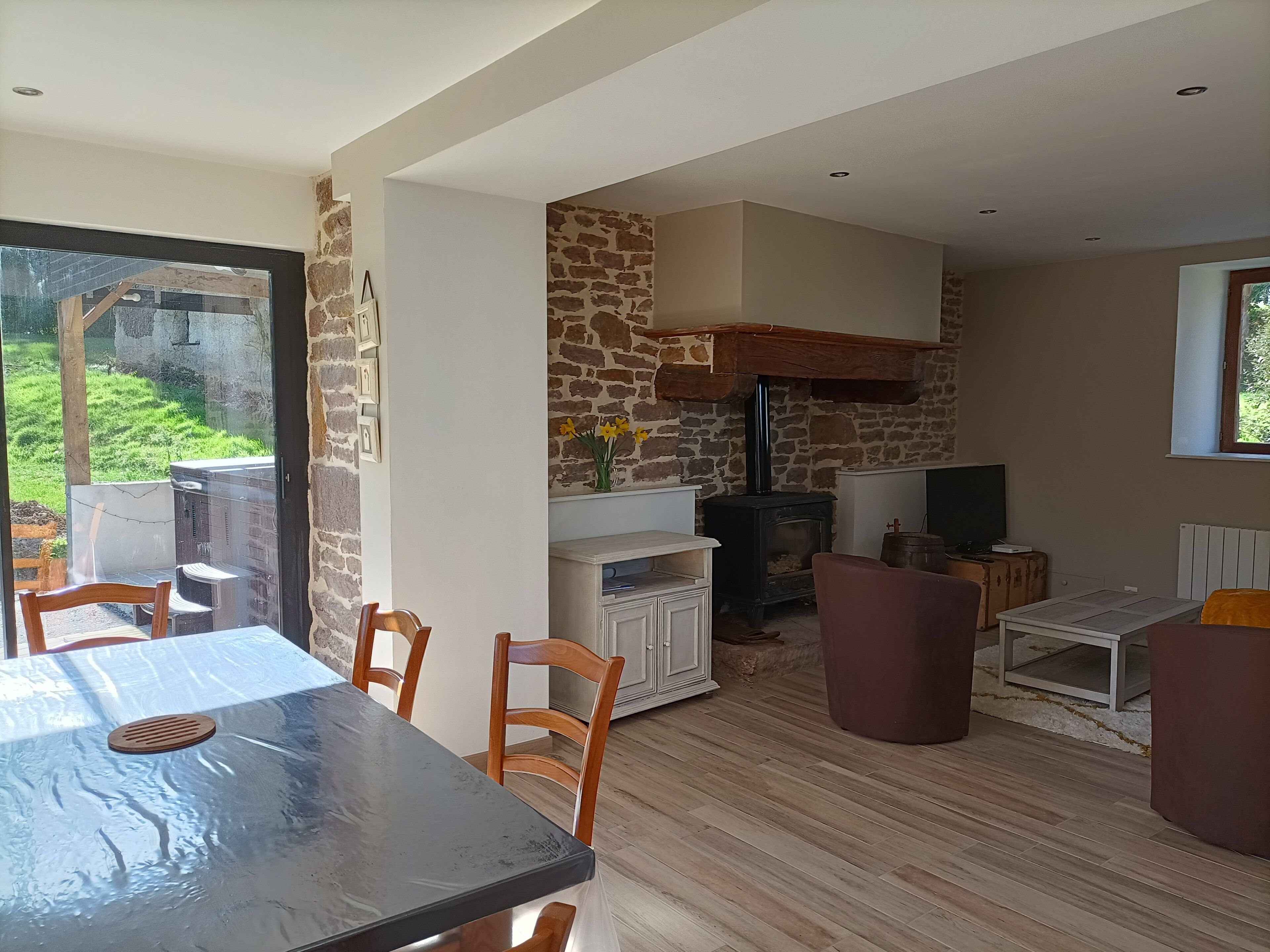 A room with a stone wall, a fireplace, a dining table, and chairs.