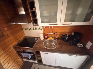 A kitchen with wooden cabinets, a stainless steel sink, a stove, and a coffee maker. - Relaxation in the Black Forest (Sasbachwalden)
