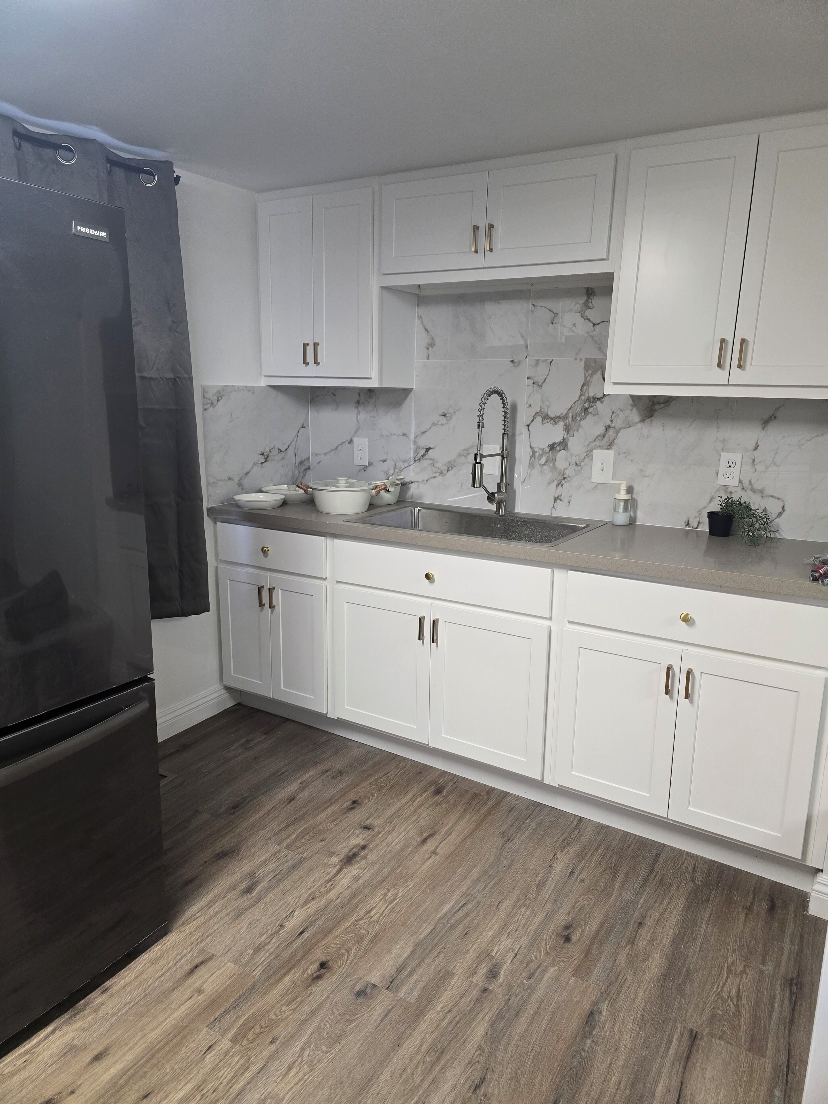 A kitchen with white cabinets, a marble backsplash, and a stainless steel refrigerator.