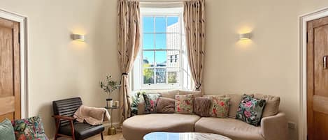 A living room with a sofa, armchairs, a coffee table, and a window with curtains.