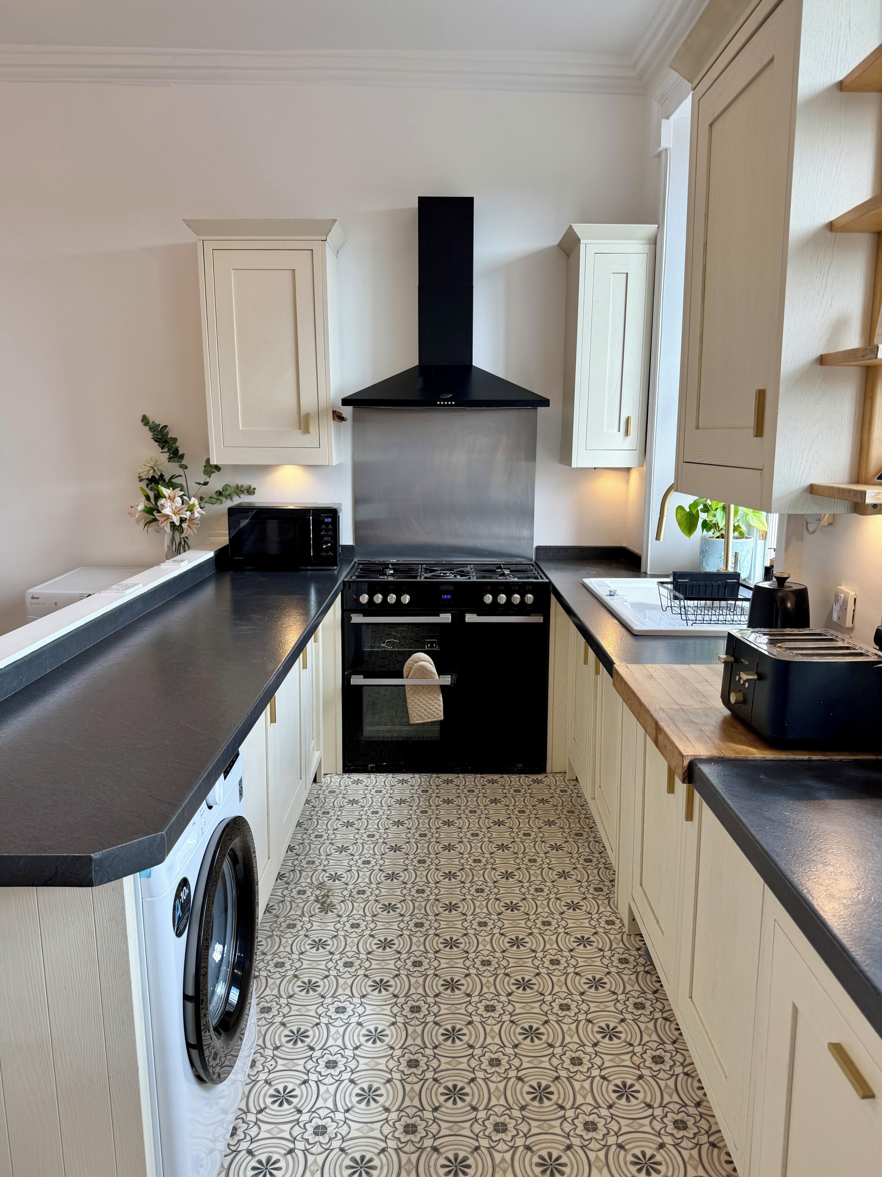 A compact kitchen with a washing machine, a stove, and a toaster.