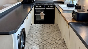 Een functionele keuken met een wasmachine, fornuis en broodrooster.