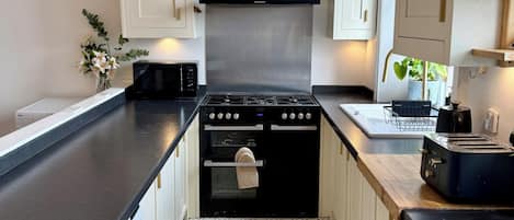 A compact kitchen with a washing machine, a stove, and a toaster.
