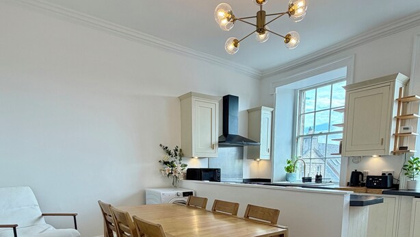 Een moderne keuken met een centraal eiland, een houten eettafel en stoelen.