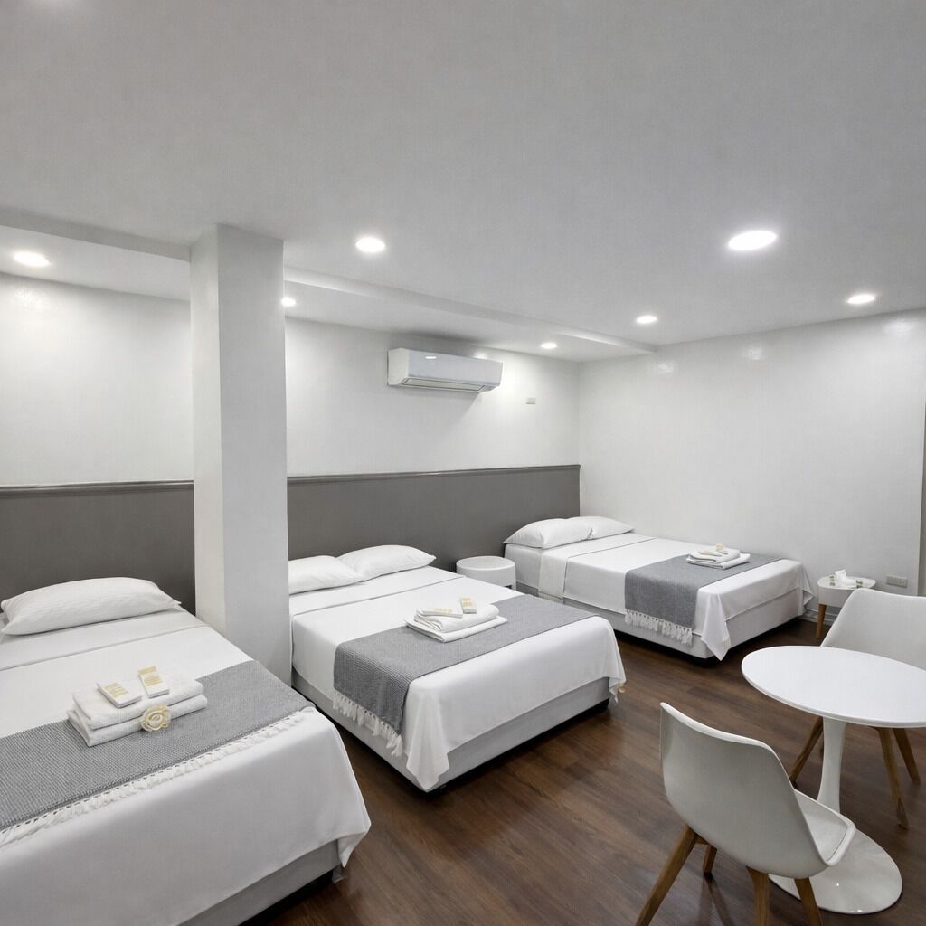 Une chambre d’hôtel avec trois lits, une petite table ronde et une chaise.