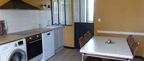 A compact kitchen with a washing machine, a sink, and a dining area with a table and chairs.