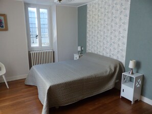 A bedroom with a bed, a radiator, a window, and a nightstand with a lamp. - 2-star rural B&B near Angoulême (16), with shops and recreational activities nearby (La Couronne)