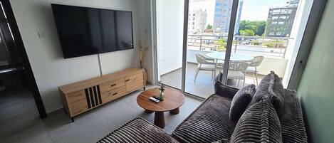 A modern living room with a flat-screen TV, a wooden console, a round coffee table, and a sofa.