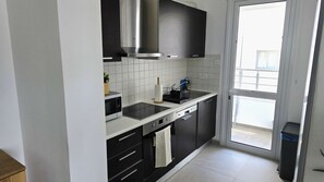 A modern kitchen with a stove, sink, and black cabinets. - Modern Apartment • Peaceful Retreat • Nature Views (Larnaca)
