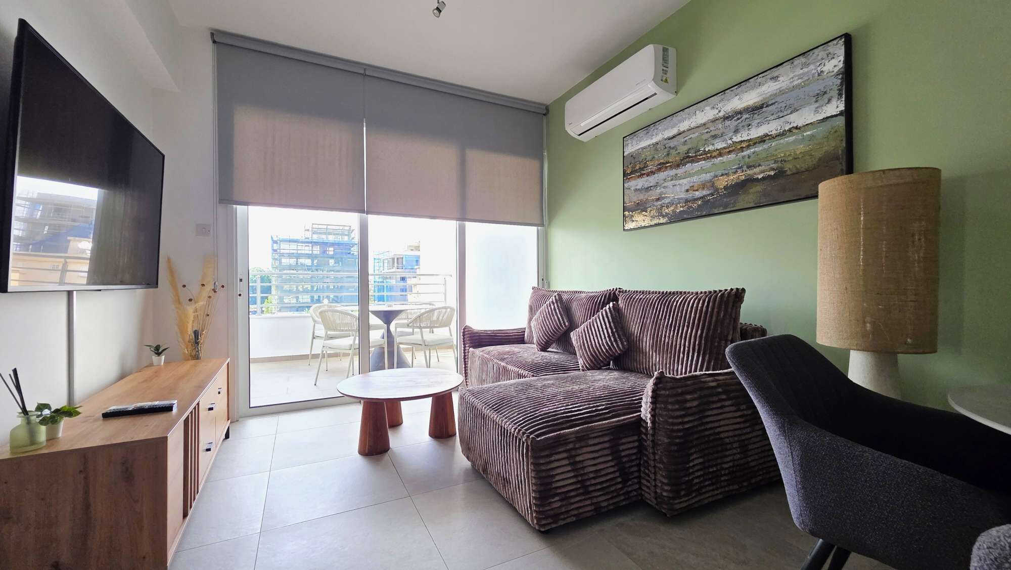 A modern living room with a sofa, a chair, a small table, and a TV.