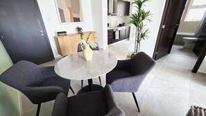 A modern living room with a round marble table, two grey armchairs, a wooden cabinet, and a potted plant. - Modern Apartment • Peaceful Retreat • Nature Views (Larnaca)
