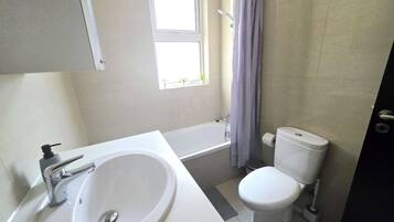 A bathroom with a bathtub, toilet, and sink.