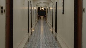 Un pasillo de hotel con suelo estampado, puertas a ambos lados y una lámpara en el techo.