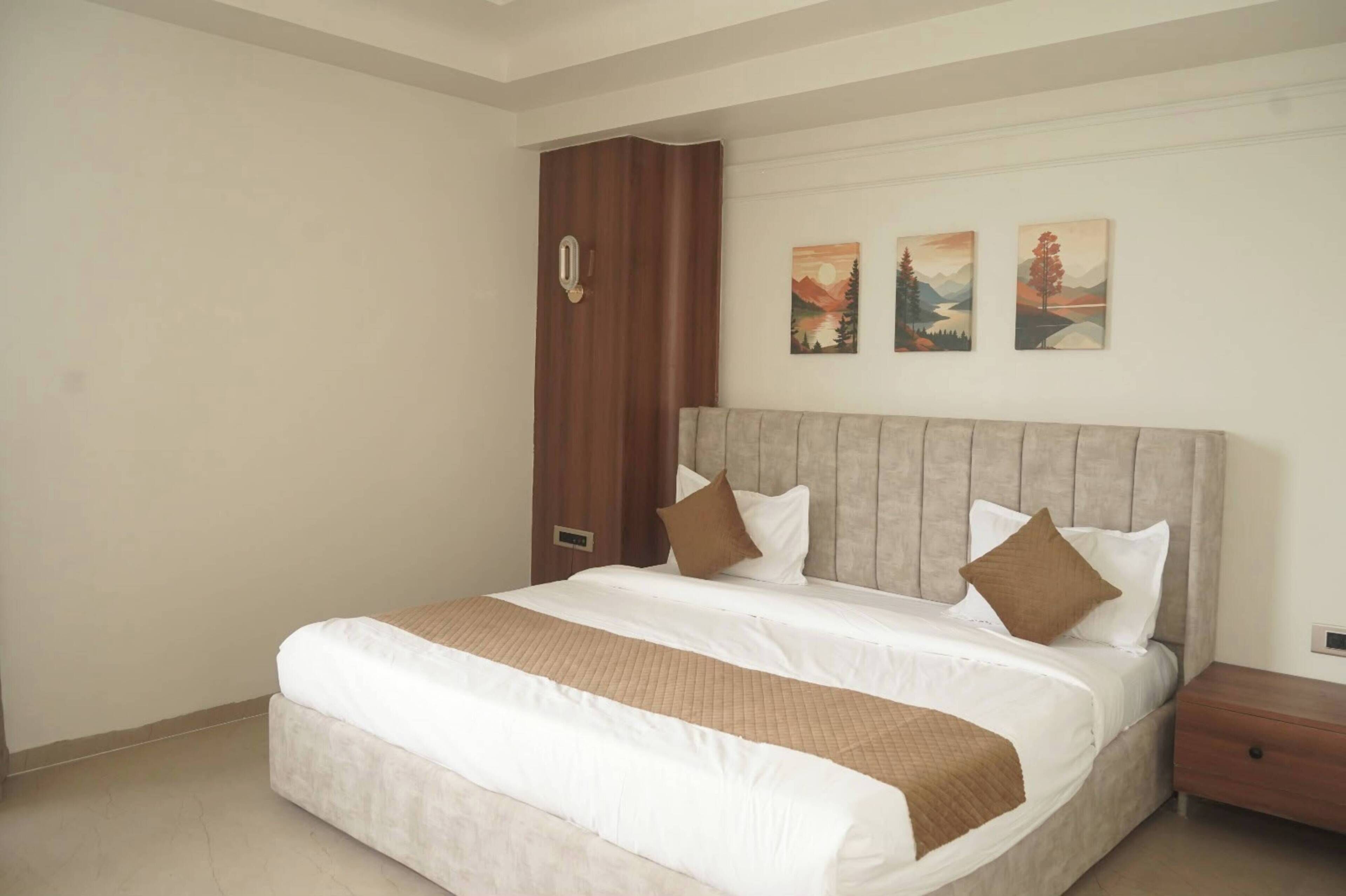 Un dormitorio con una cama grande, un armario de madera y tres cuadros de paisajes en la pared.