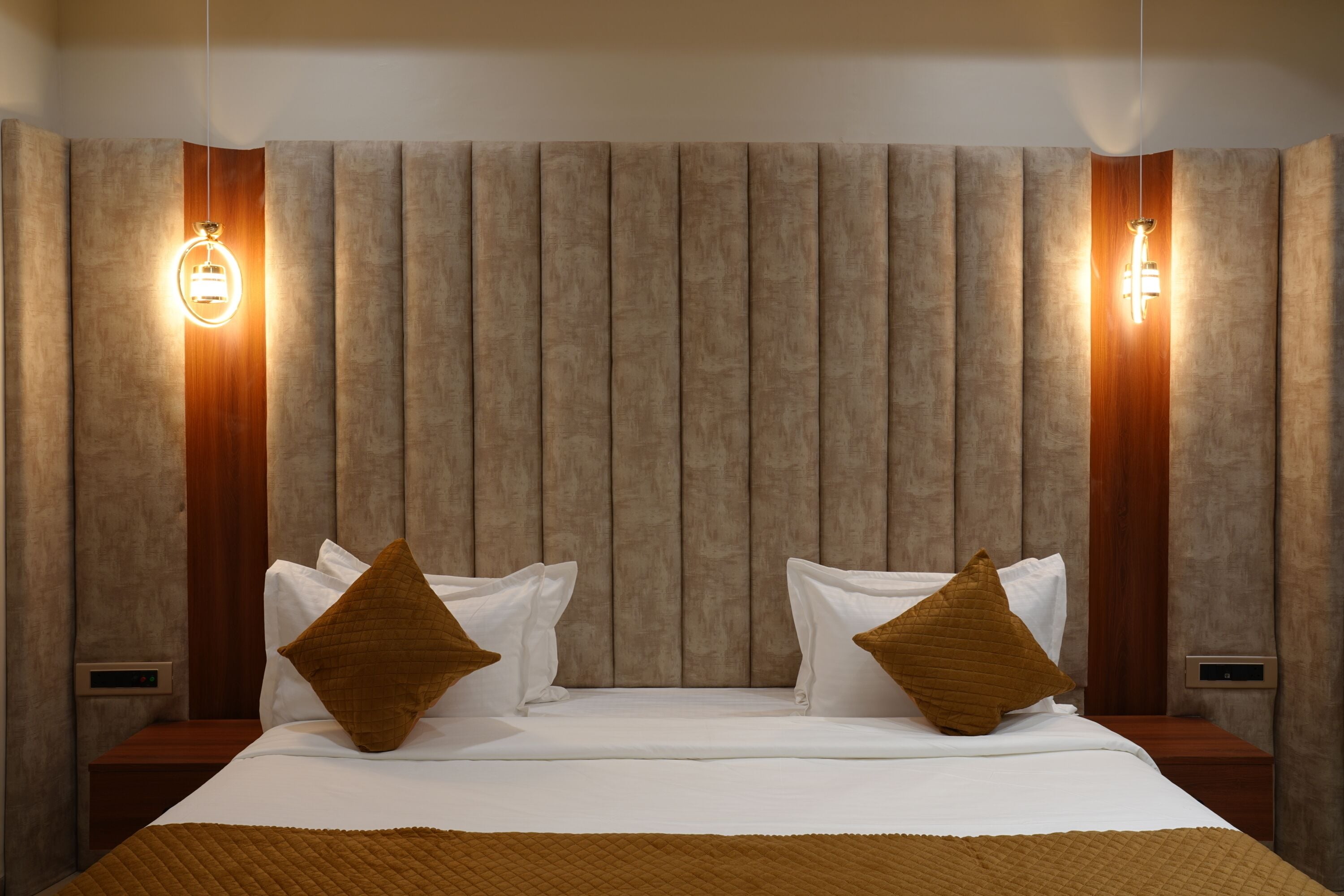 Una habitación de hotel con una cama grande, dos mesitas de noche y un cabecero con paneles verticales.