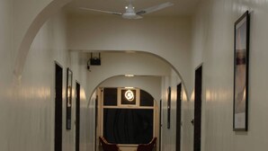 Un pasillo con piso estampado, arcos en las puertas y cuadros en las paredes.