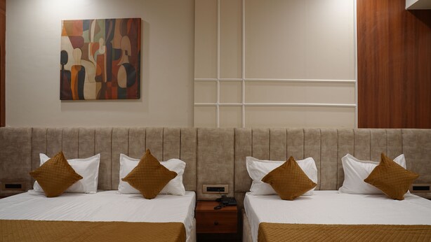 Habitación de hotel con dos camas, una mesita de noche, un teléfono y un cuadro abstracto colgado en la pared.