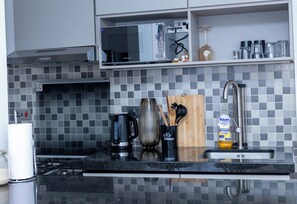 Uma cozinha moderna com fogão a gás, cafeteira, bloco de facas e um frasco de detergente.