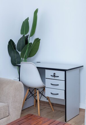 Uma mesa de escritório moderna com uma cadeira branca, uma planta verde grande e uma mesa de centro de madeira.