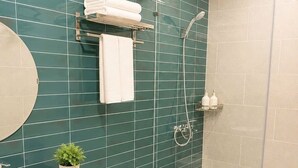 Un baño con ducha, inodoro, lavamanos y un perchero para toallas.