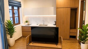 Una cocina moderna con televisión integrada, armarios de madera, un fregadero y plantas en macetas.