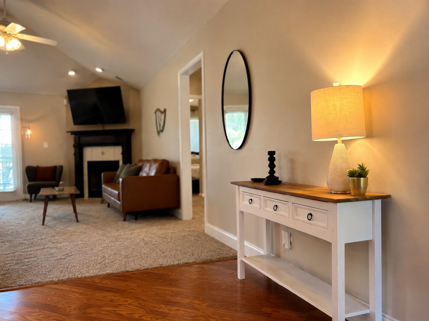 A living room with a fireplace, a television, a sofa, a coffee table, and a console table with a lamp and decorative items.