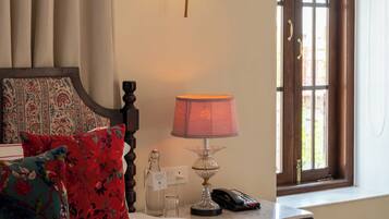 A hotel room with a bed, a nightstand, a lamp, a telephone, and a window with curtains.