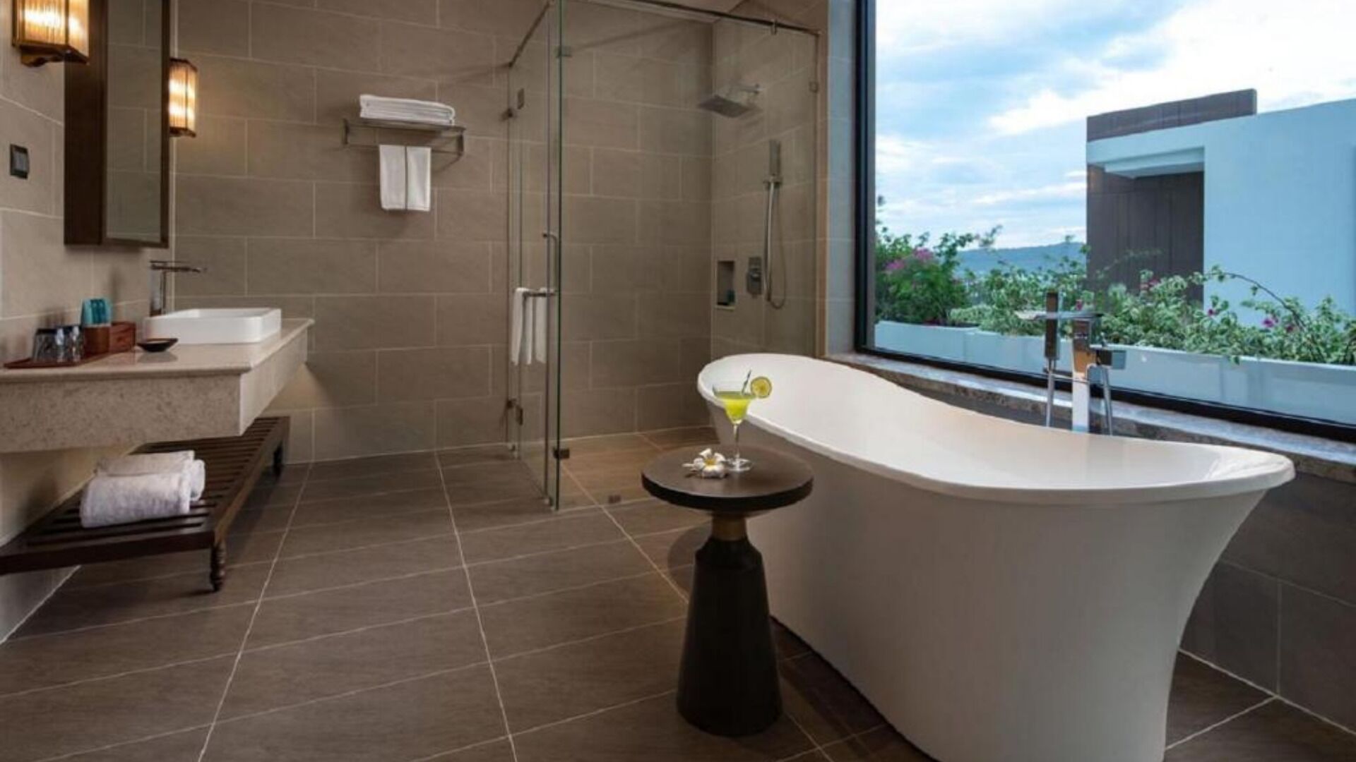 Un baño moderno con una bañera independiente, una ducha con cerramiento de vidrio y un amplio ventanal con vistas al verdor.