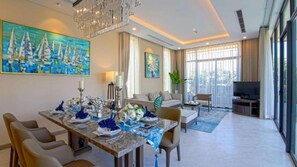 A modern dining area with a table set for four, a sofa, a television, and large windows.