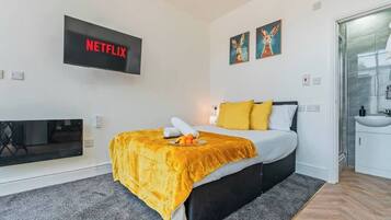 Een moderne hotelkamer met een bed, een aan de muur bevestigde televisie en kunst boven het bed.