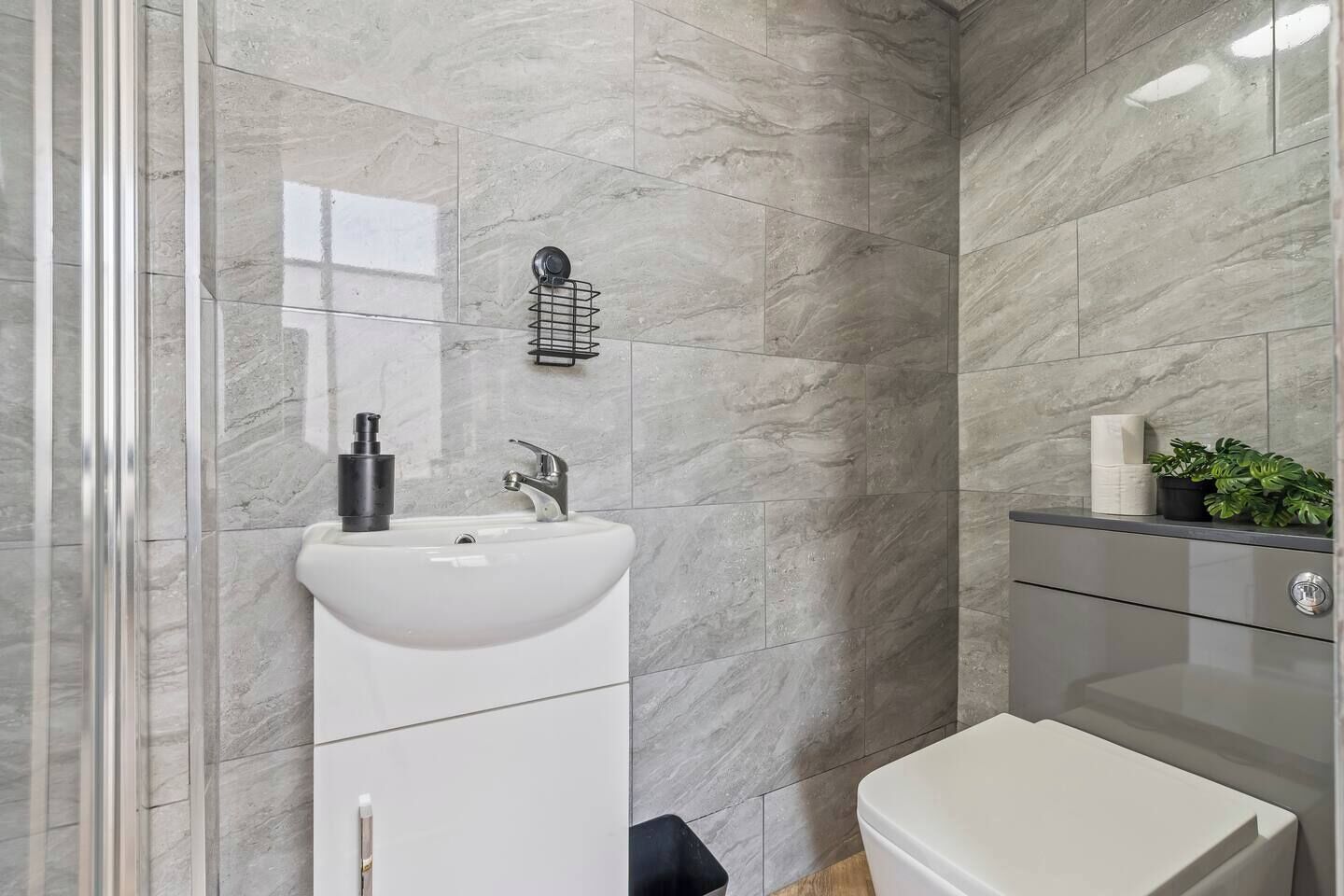 A modern bathroom with a white sink, a mirror, a towel rack, and a toilet.