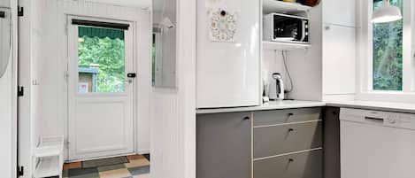 A kitchen with white cabinets, a Siemens dishwasher, and a window with a view of greenery.
