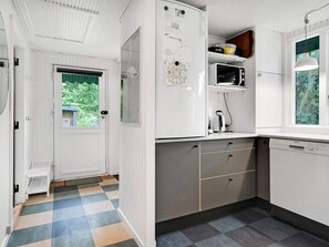 A kitchen with white cabinets, a Siemens dishwasher, and a window with a view of greenery.
