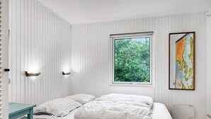 Un dormitorio con una cama, un ventanal con vistas a zonas verdes y un mapa colgado en la pared.
