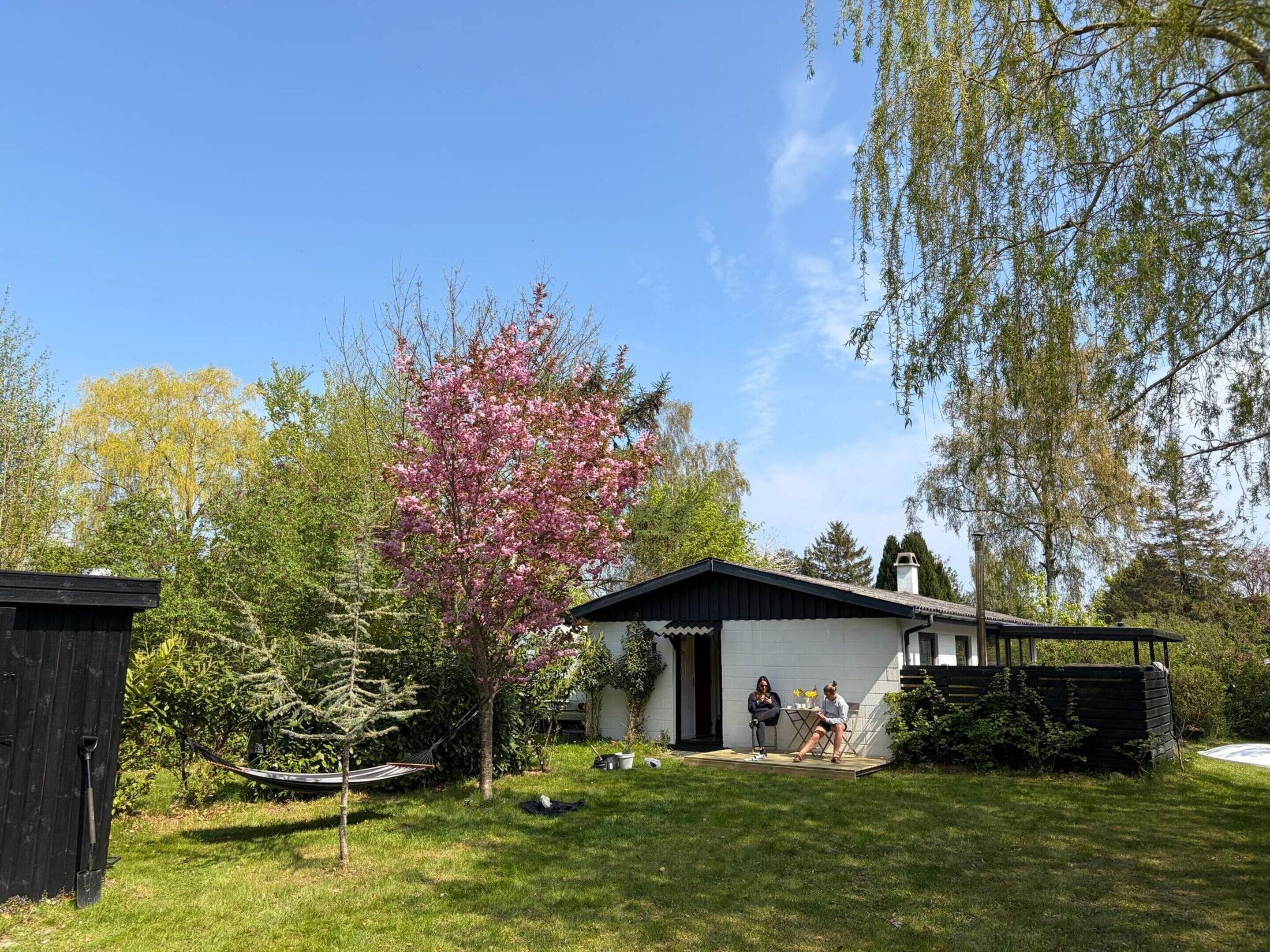A residential property with a white house, a black roof, and a garden.