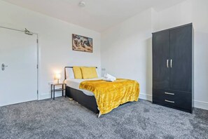Ein Schlafzimmer mit einem Bett, einem Nachttisch, einem Kleiderschrank und einem Bild an der Wand.