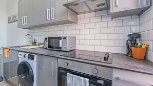 Et moderne køkken med rustfrie hvidevarer, en indbygget vaskemaskine og et flisebeklædt bagpanel.
