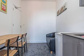 Eine kompakte Küchenzeile mit Kühlschrank, Spüle und einer Essecke mit Tisch und Stühlen.