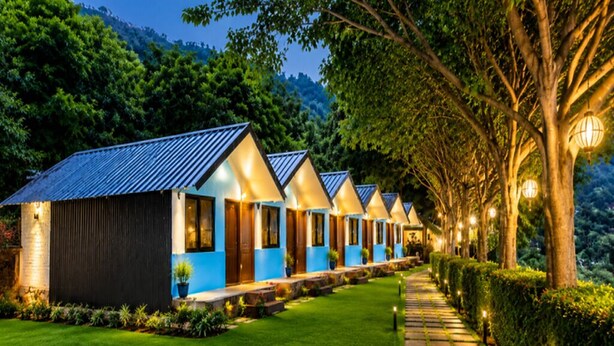 A row of modern, well-lit cabins with a pathway leading through a landscaped garden.