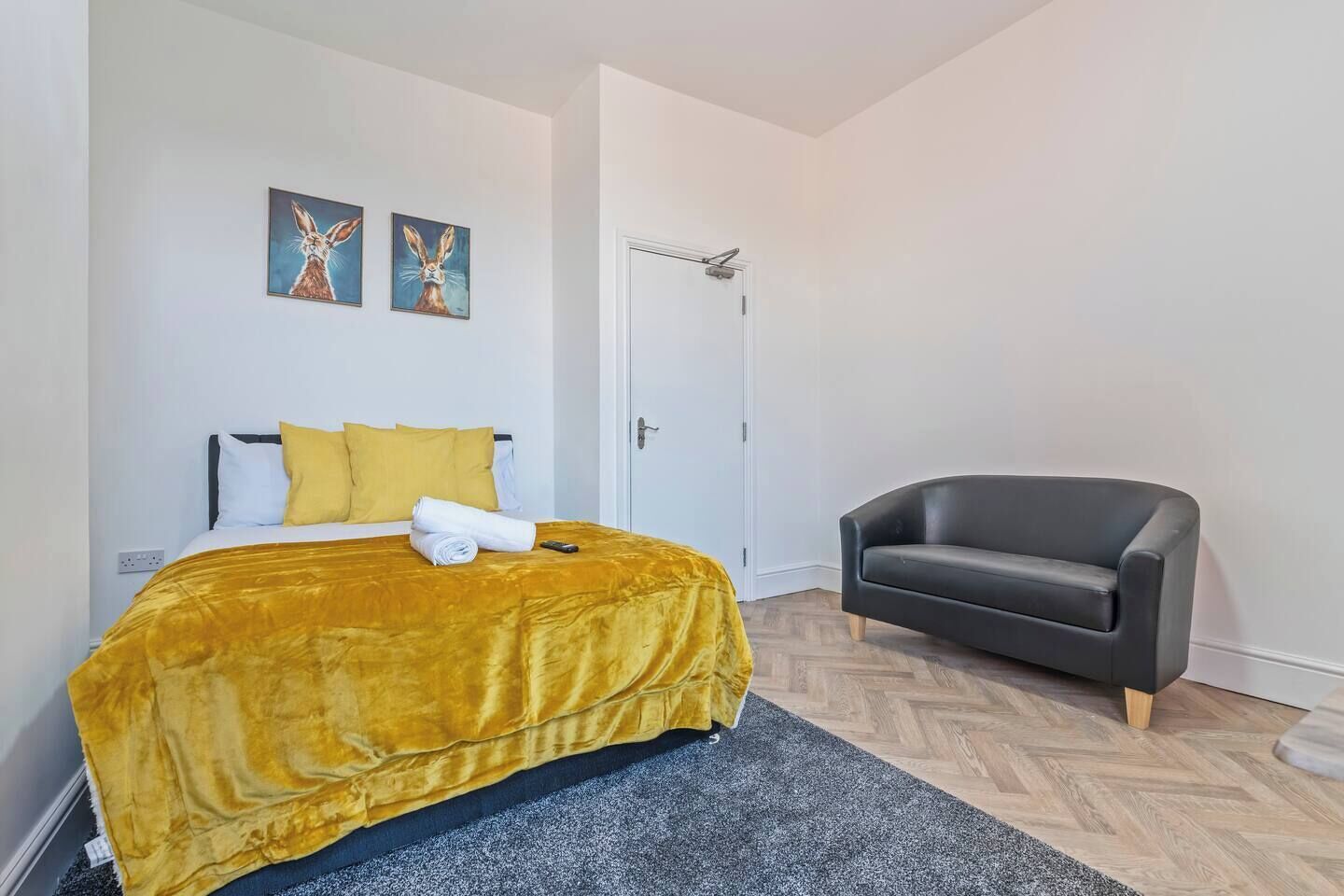 Een hotelkamer met een bed, een stoel en twee schilderijen aan de muur.