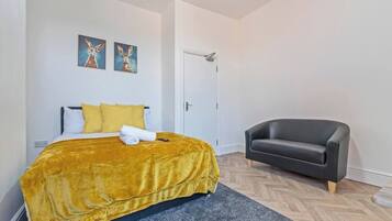 Een hotelkamer met een bed, een stoel en twee schilderijen aan de muur.
