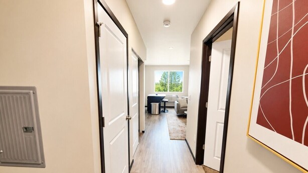 A hallway with a door on the left, a framed artwork on the right, and a view into a living area with a sofa and a coffee table. - Stylish 2BR Tacoma Stay | Near Hospitals & Tacoma Dome (Tacoma)