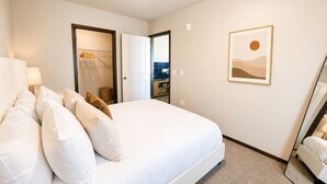 A hotel room with a bed, a bedside table, a lamp, a wardrobe, and a framed picture on the wall. - Stylish 2BR Tacoma Stay | Near Hospitals & Tacoma Dome (Tacoma)