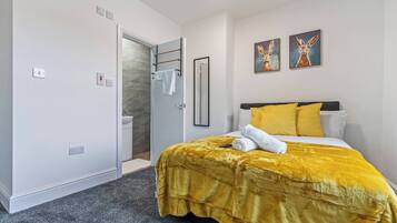 Una habitación de hotel con cama, baño y puerta que da a una zona de ducha.