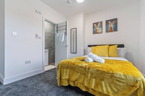 Une chambre d’hôtel comprenant un lit, une salle de bain et une porte donnant accès à un espace douche.